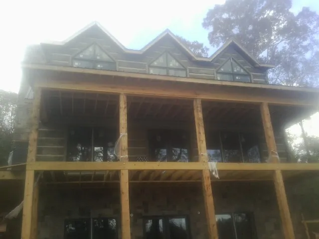 Dormers and porch framing on a large log home under construction — Roof Coating work by our crew in Trout Lake