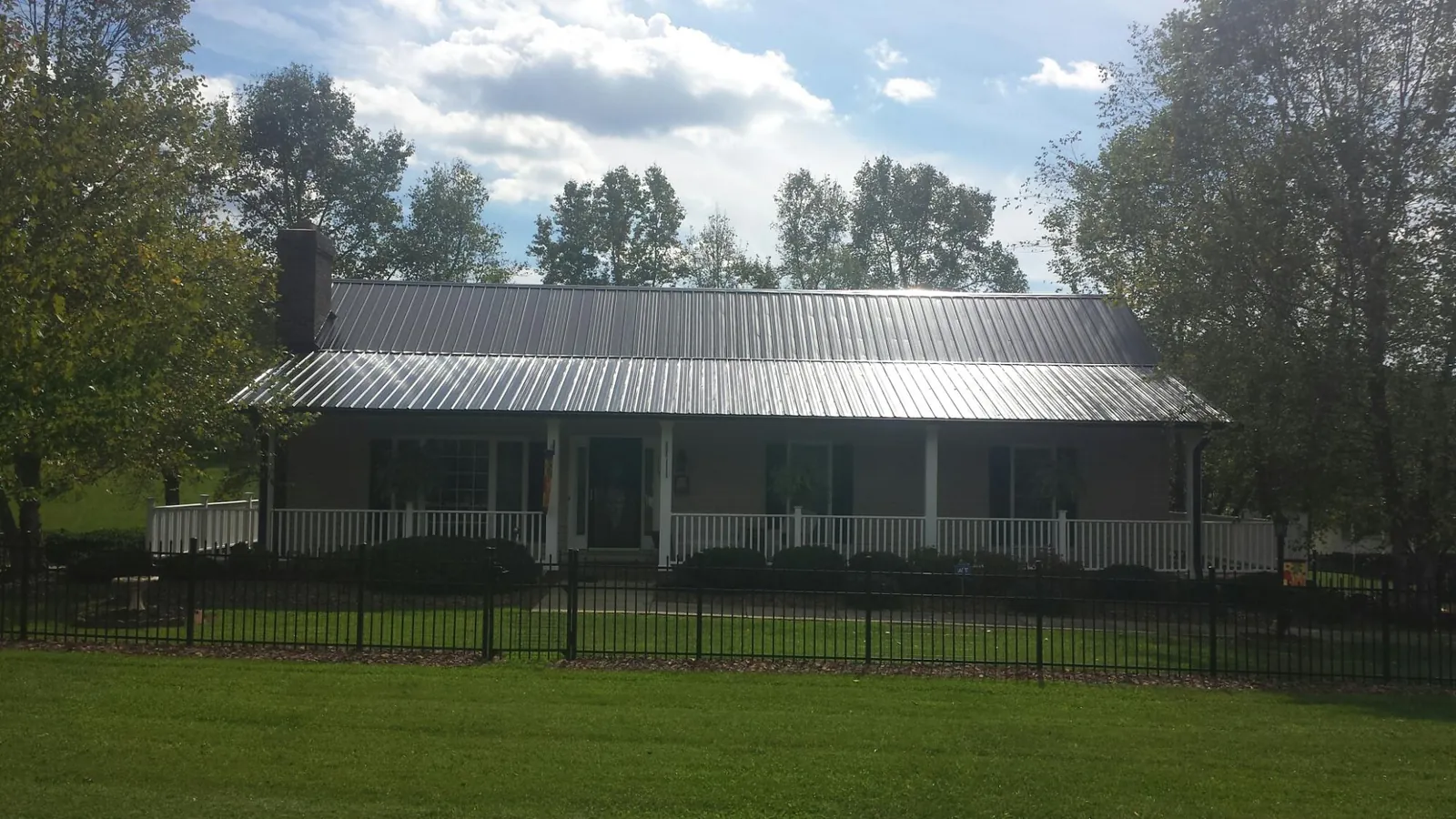 Gray metal roof on a brick ranch with a full width front porch — Gutter Guard Installation work by our crew in Trout Lake