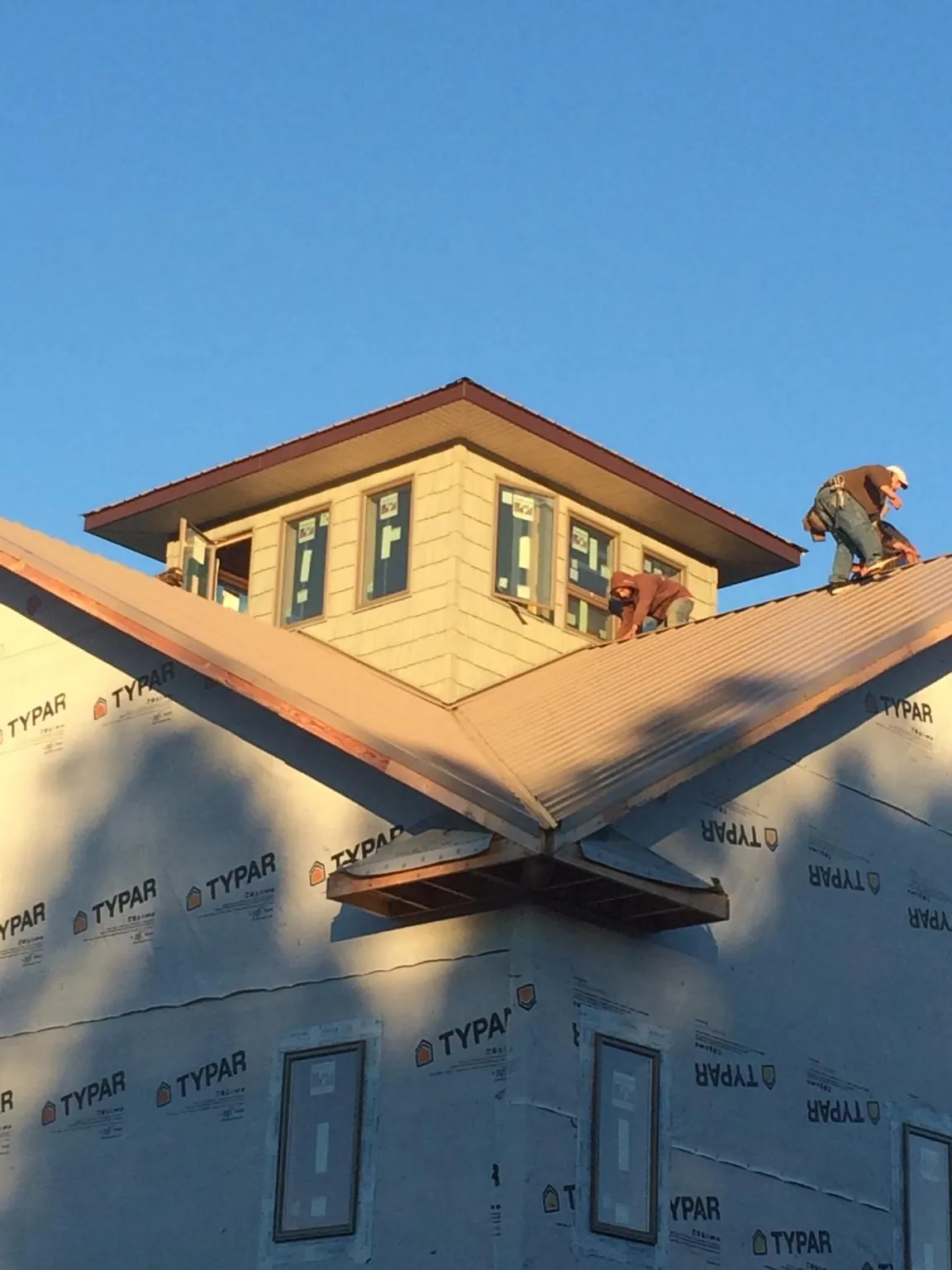 Roofers working around a rooftop cupola on a new metal roof at sunset — Roof Waterproofing in Trout Lake by Roofing Brothers